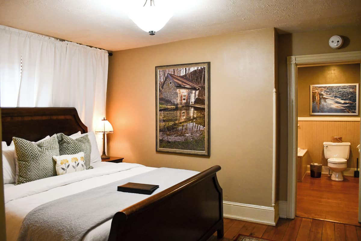 A neatly made bed with a wooden headboard, a bedside lamp, and a framed picture on the wall.