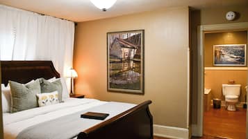 A neatly made bed with a wooden headboard, a bedside lamp, and a framed picture on the wall.