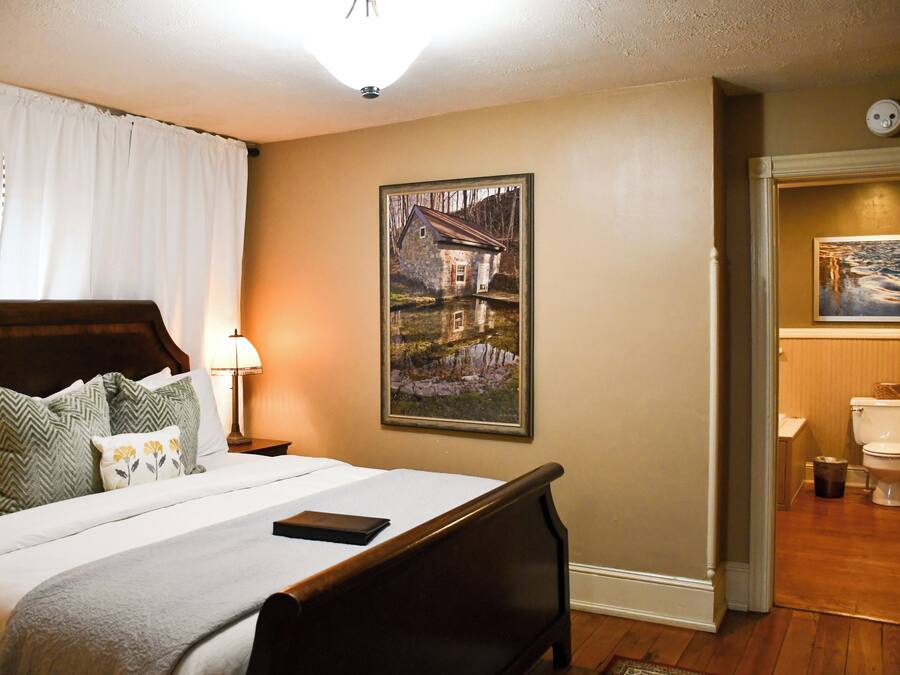 A neatly made bed with a wooden headboard, a bedside lamp, and a framed picture on the wall.