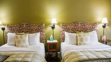 Ein Hotelzimmer mit zwei Betten, jeweils mit einem floralen Kopfteil, Nachttischlampen und passenden Kissen.