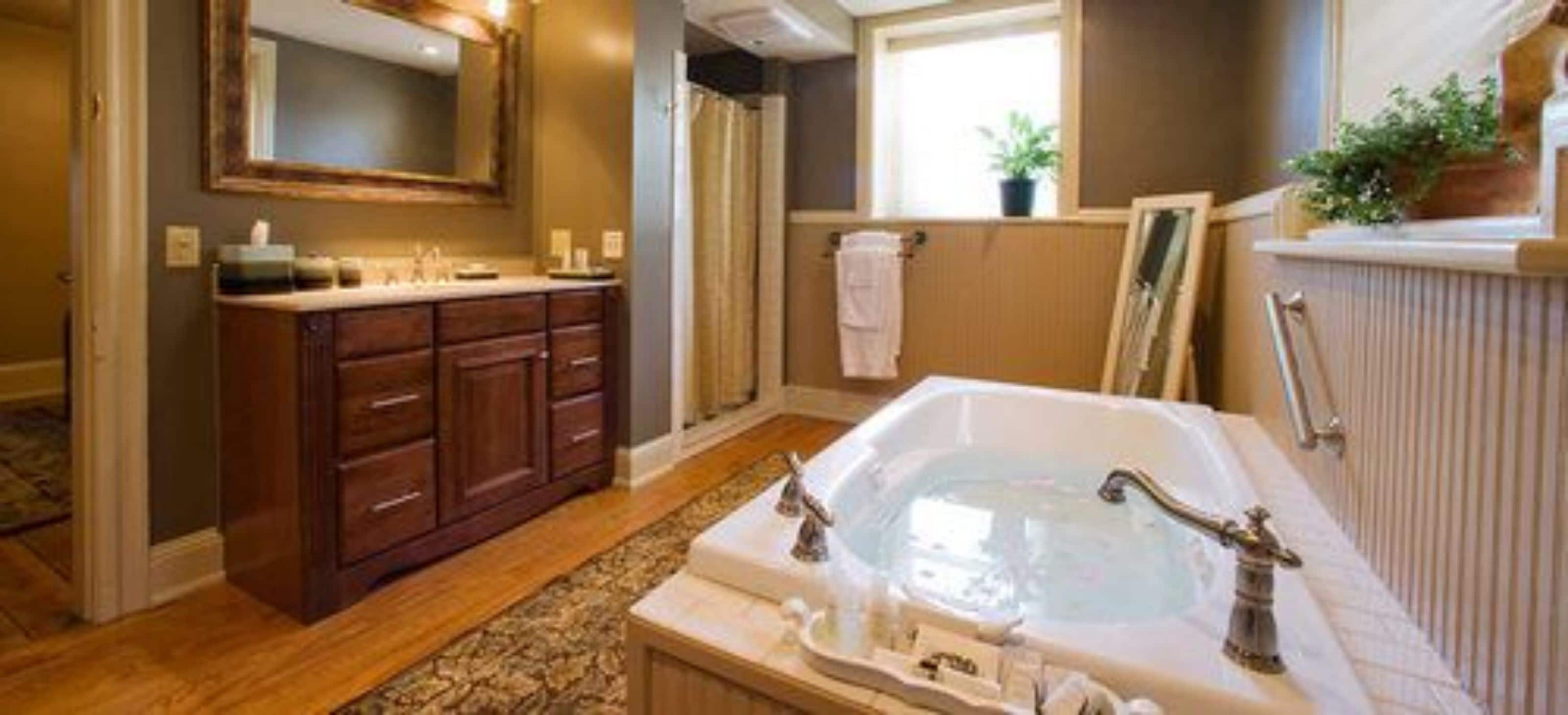 A bathroom with a large bathtub, wooden vanity, and a mirror above the sink.