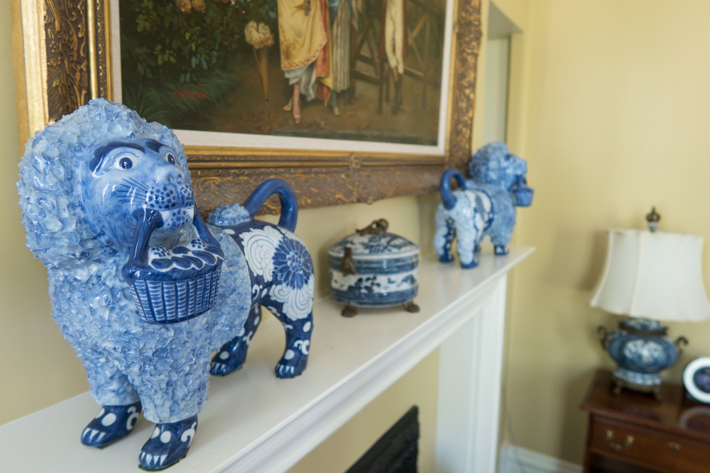 Una repisa de chimenea con figuritas azules de cerámica de elefantes y un pequeño recipiente azul y blanco de cerámica.