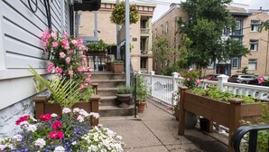 A residential building with a front porch, steps leading to a door, and a white picket fence. - The Inn on Negley (Pittsburgh)