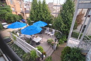 A rooftop patio with blue umbrellas, outdoor furniture, and potted plants. - The Inn on Negley (Pittsburgh)