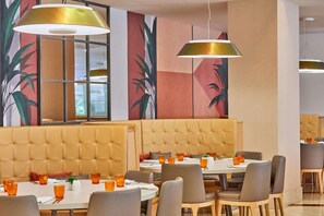 A restaurant with booths and tables, featuring a large window and a mural on the wall. - Zafiro Tropic (Alcúdia)