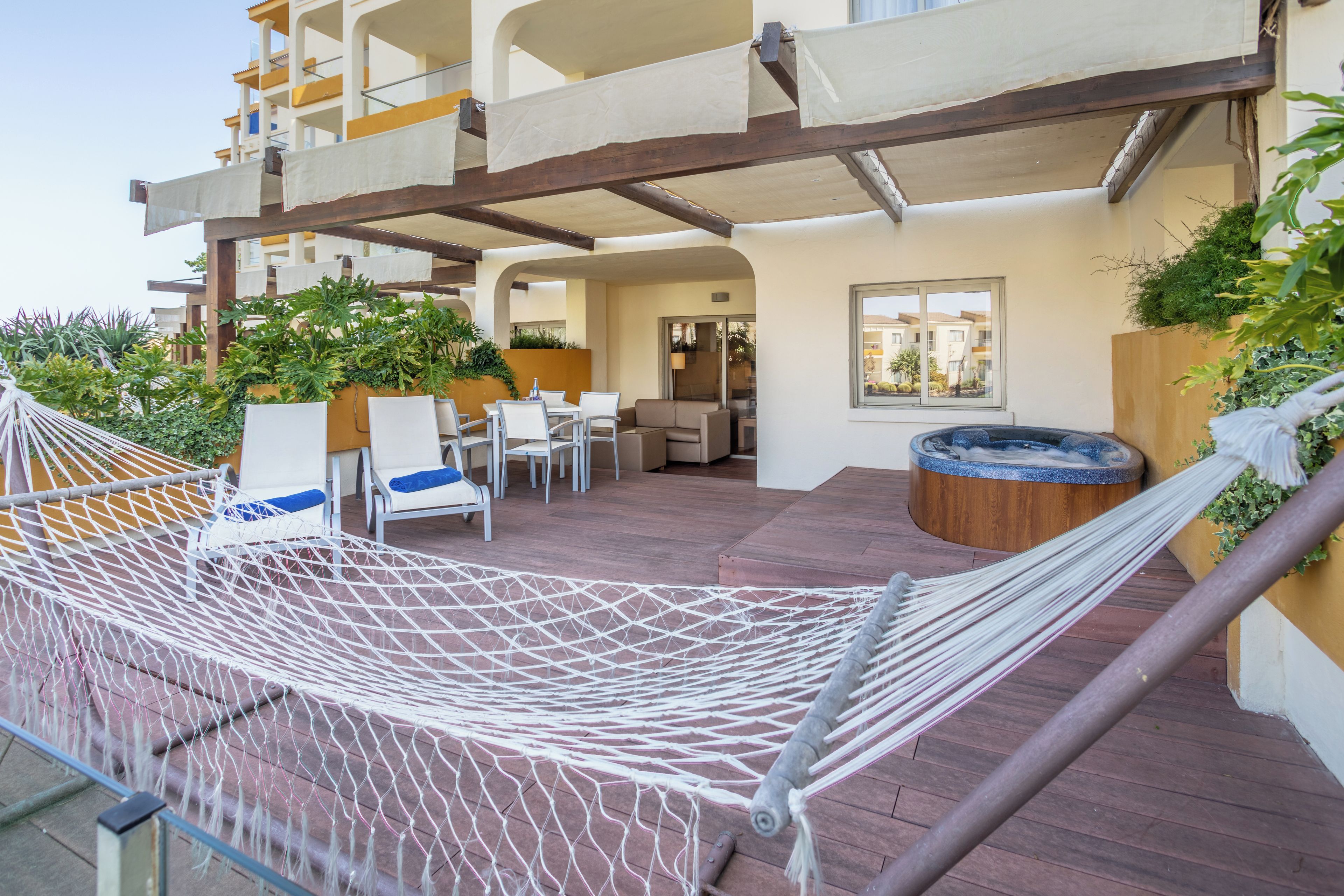 A rooftop terrace with a hammock, outdoor seating, and a hot tub.
