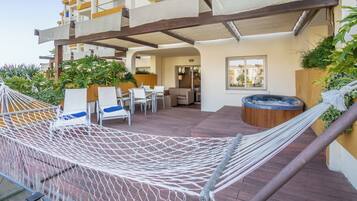 Una terraza en la azotea con una hamaca, mobiliario de exterior y un jacuzzi.