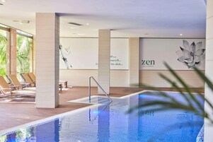 Zona de piscina con sillones reclinables y un muro con un gran mural floral.