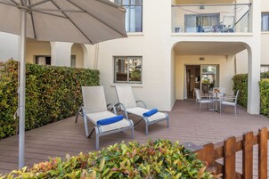 Un espacio de patio con dos sillones, una mesa y una sombrilla grande.