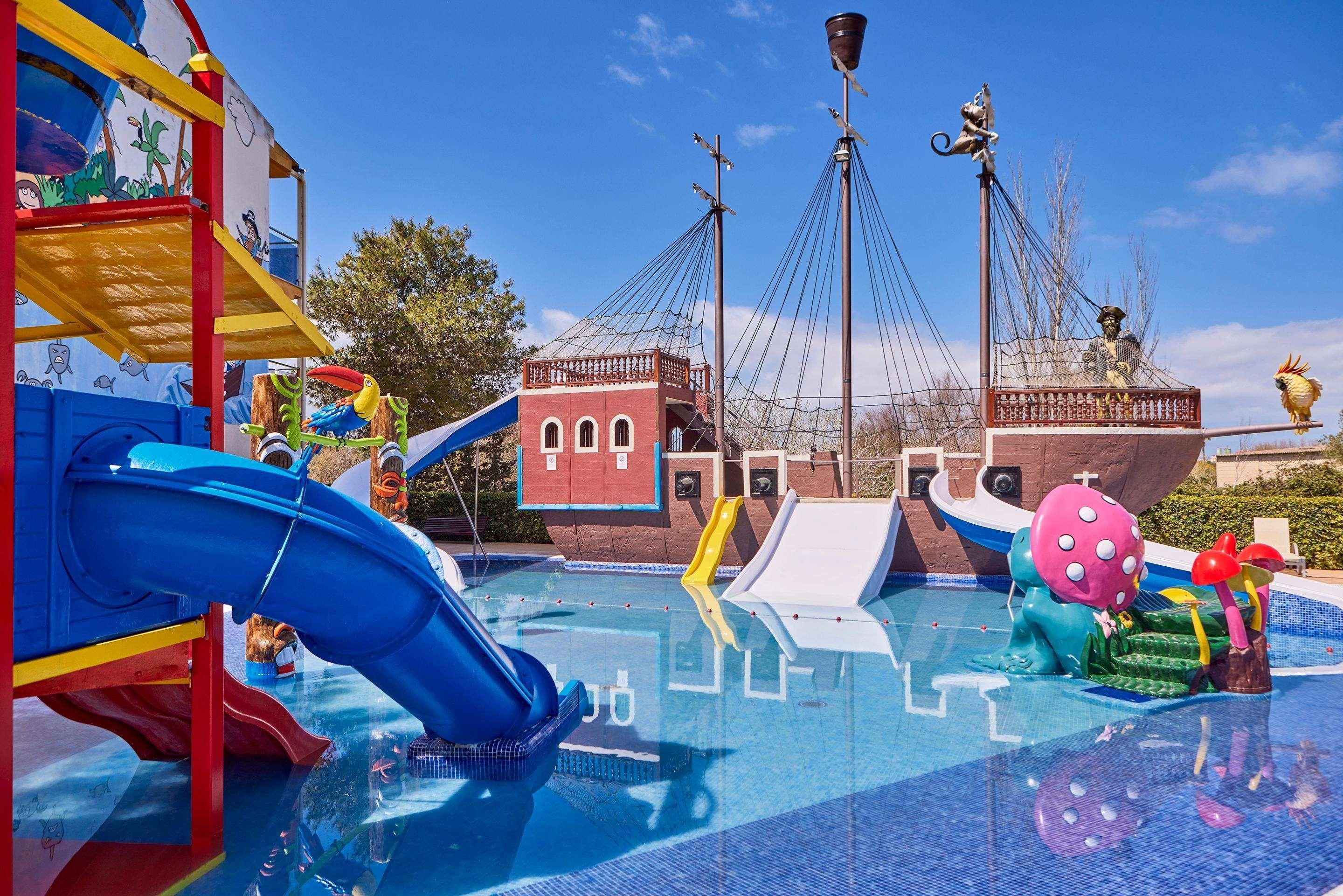 Un parque acuático con toboganes, un barco pirata y una estructura de juegos.