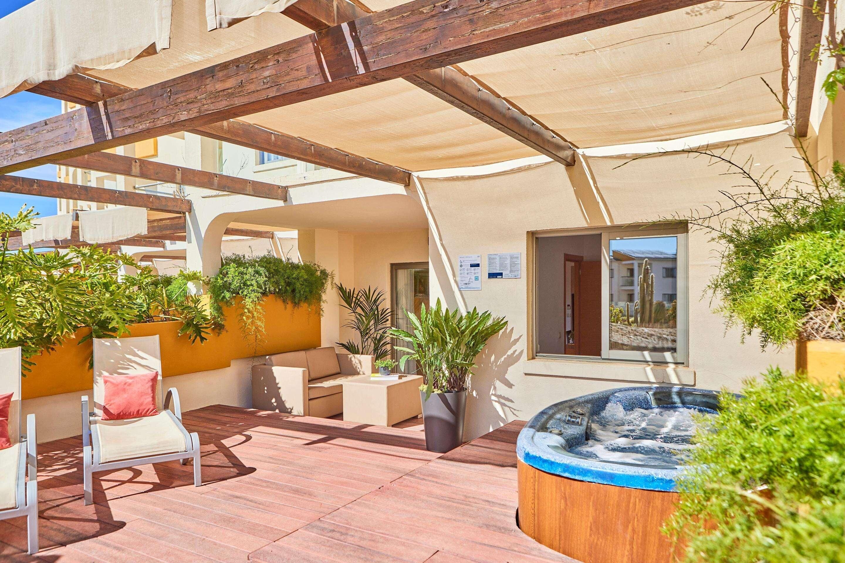 Un patio al aire libre con jacuzzi, asientos y plantas en macetas.