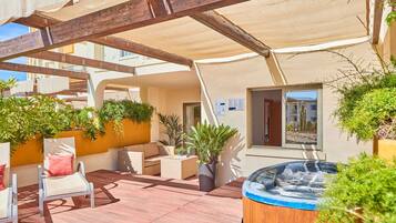 Un patio al aire libre con jacuzzi, asientos y plantas en macetas.
