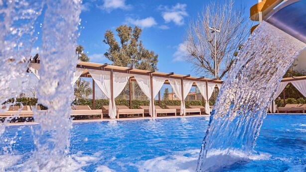 Una piscina con fuentes de agua y sillas de descanso.