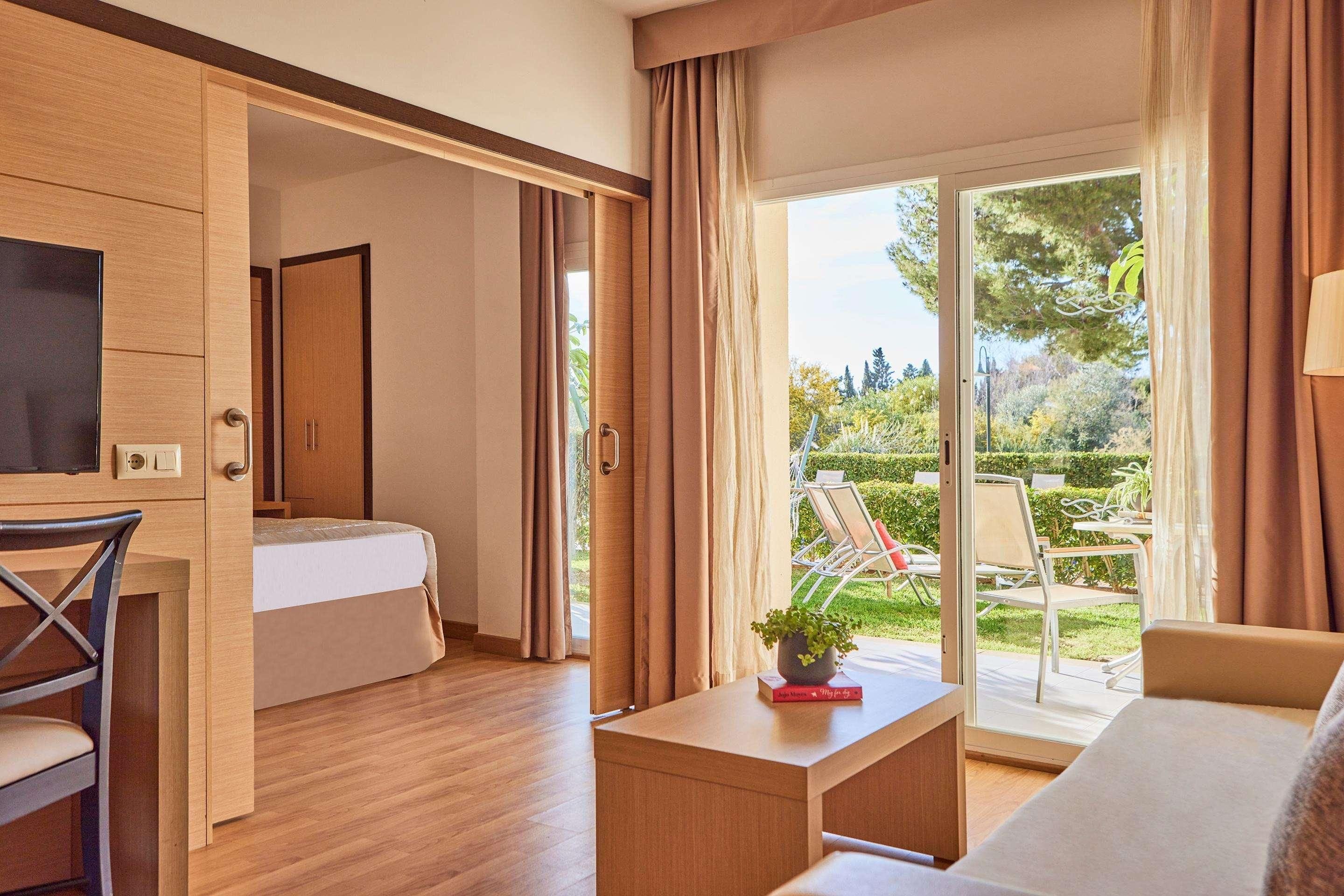 Une chambre moderne avec un lit, un bureau et une vue sur un jardin.