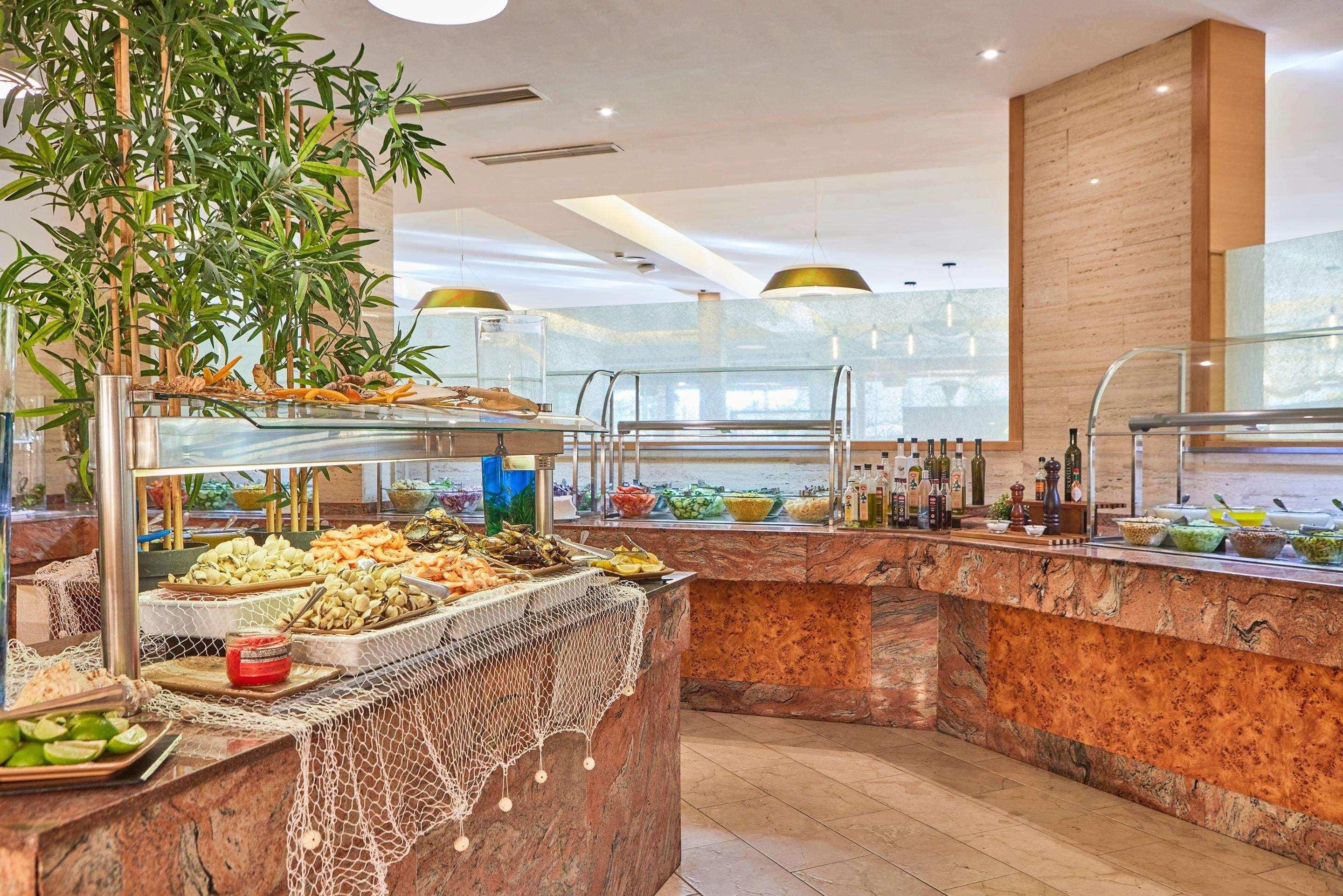 Un área de buffet con diversas opciones de comida, una barra de mármol y una planta grande.