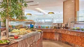 Un área de buffet con diversas opciones de comida, una barra de mármol y una planta grande.