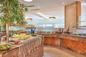 Un área de buffet con diversas opciones de comida, una barra de mármol y una planta grande.