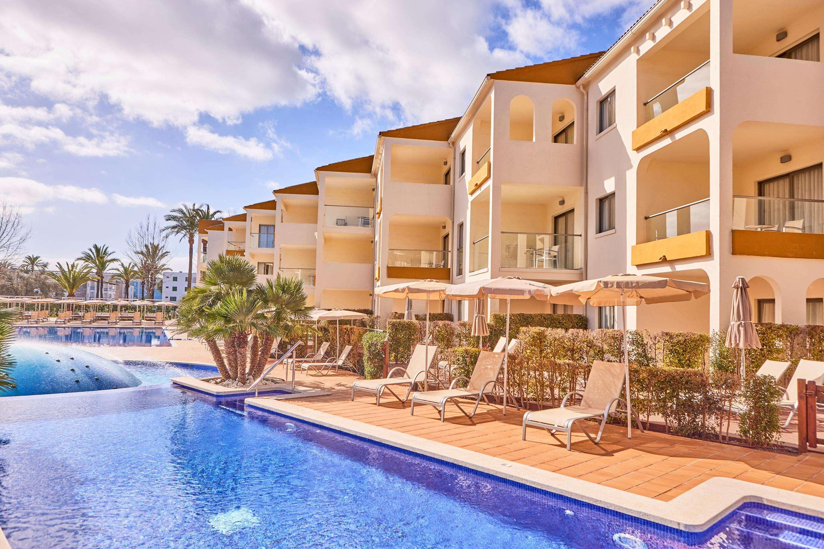 Un hotel con piscina, tumbonas y sombrillas.
