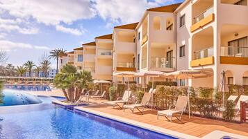 Un hotel con piscina, tumbonas y sombrillas.