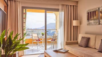 Ein modernes Hotelzimmer mit Balkon, einer Sitzecke, einem Tisch und Blick auf die Stadt.