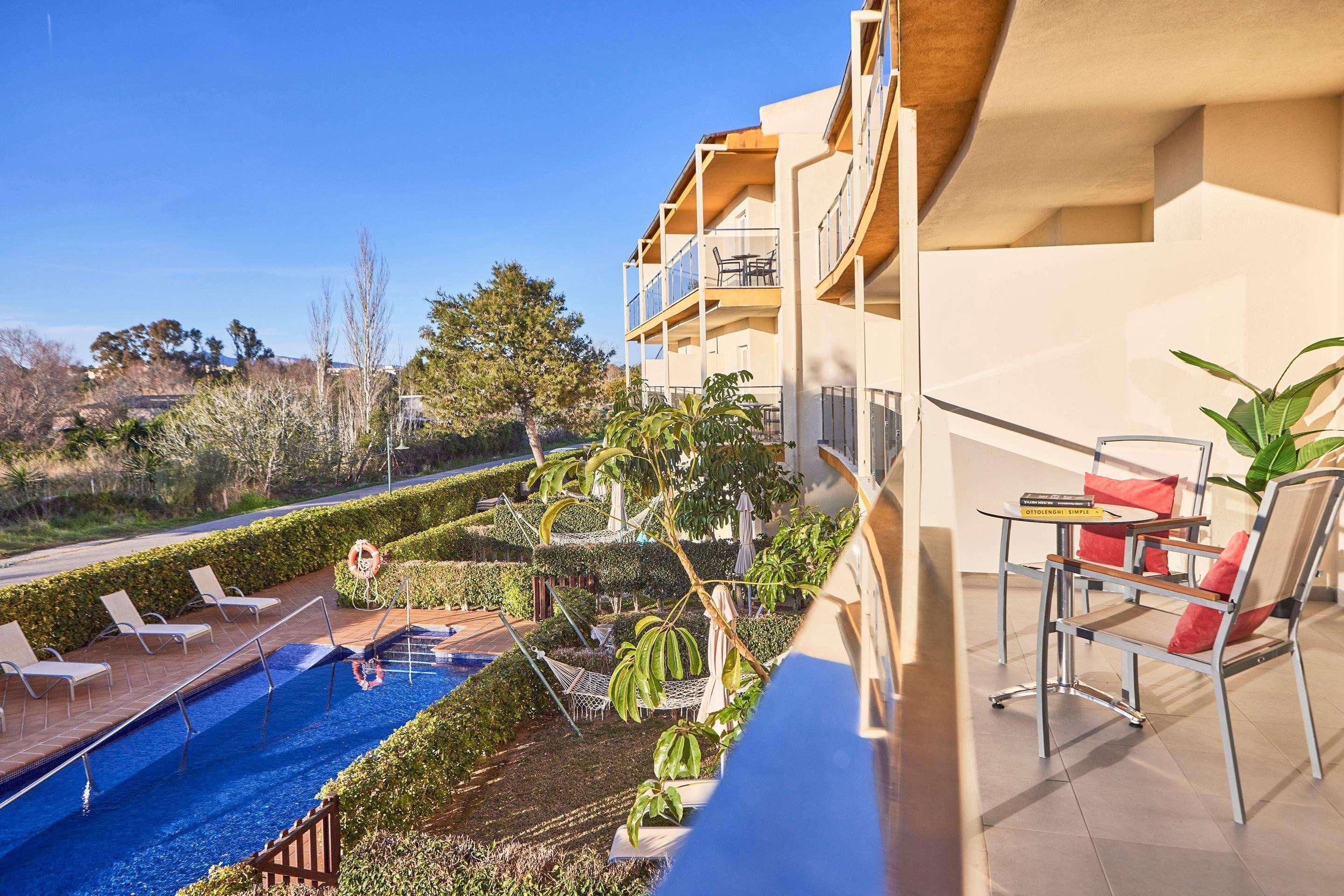 Zona de piscina con sillones de descanso, una piscina pequeña y vistas del paisaje circundante.