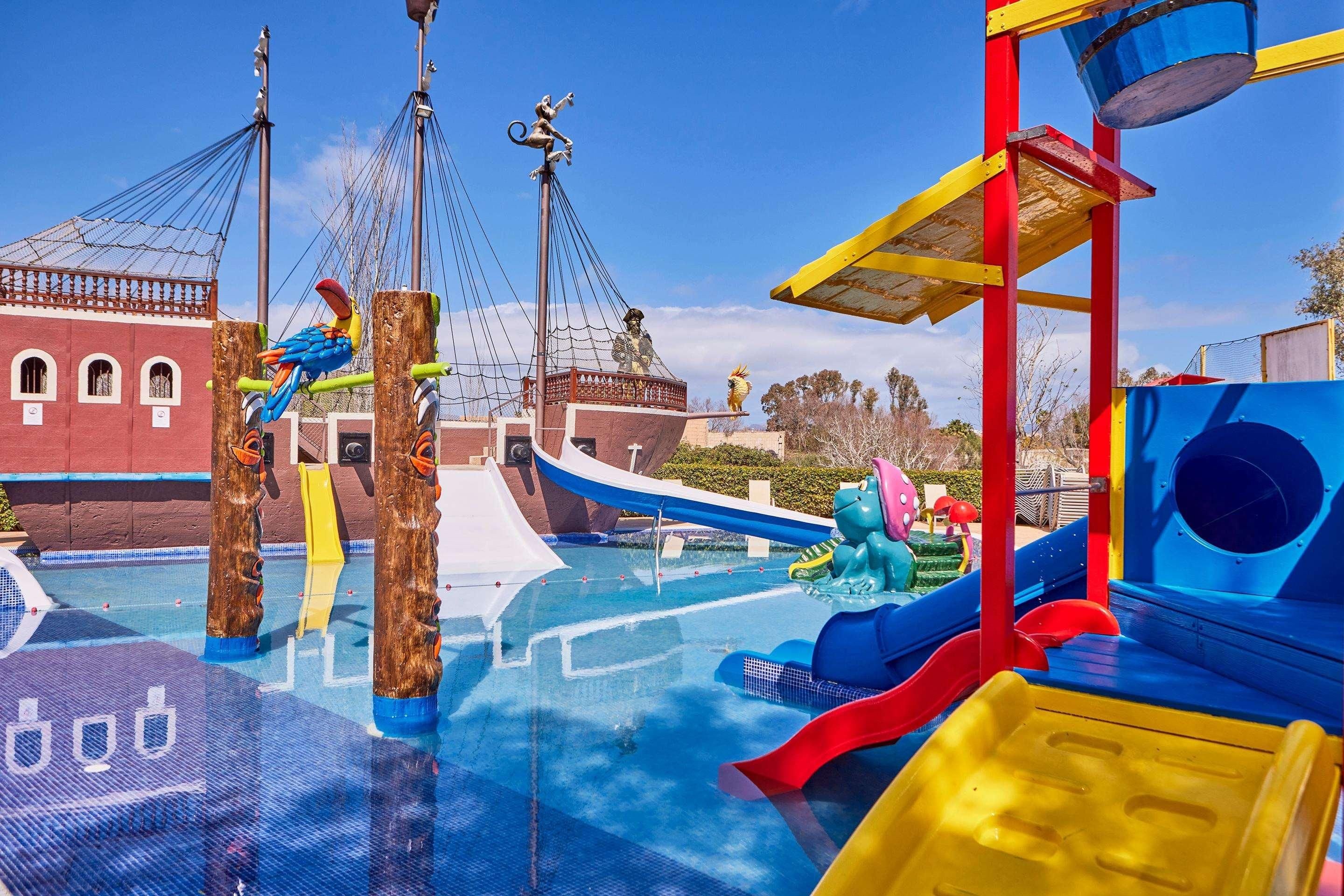 Parque acuático con toboganes, un barco pirata y una estructura de juegos.