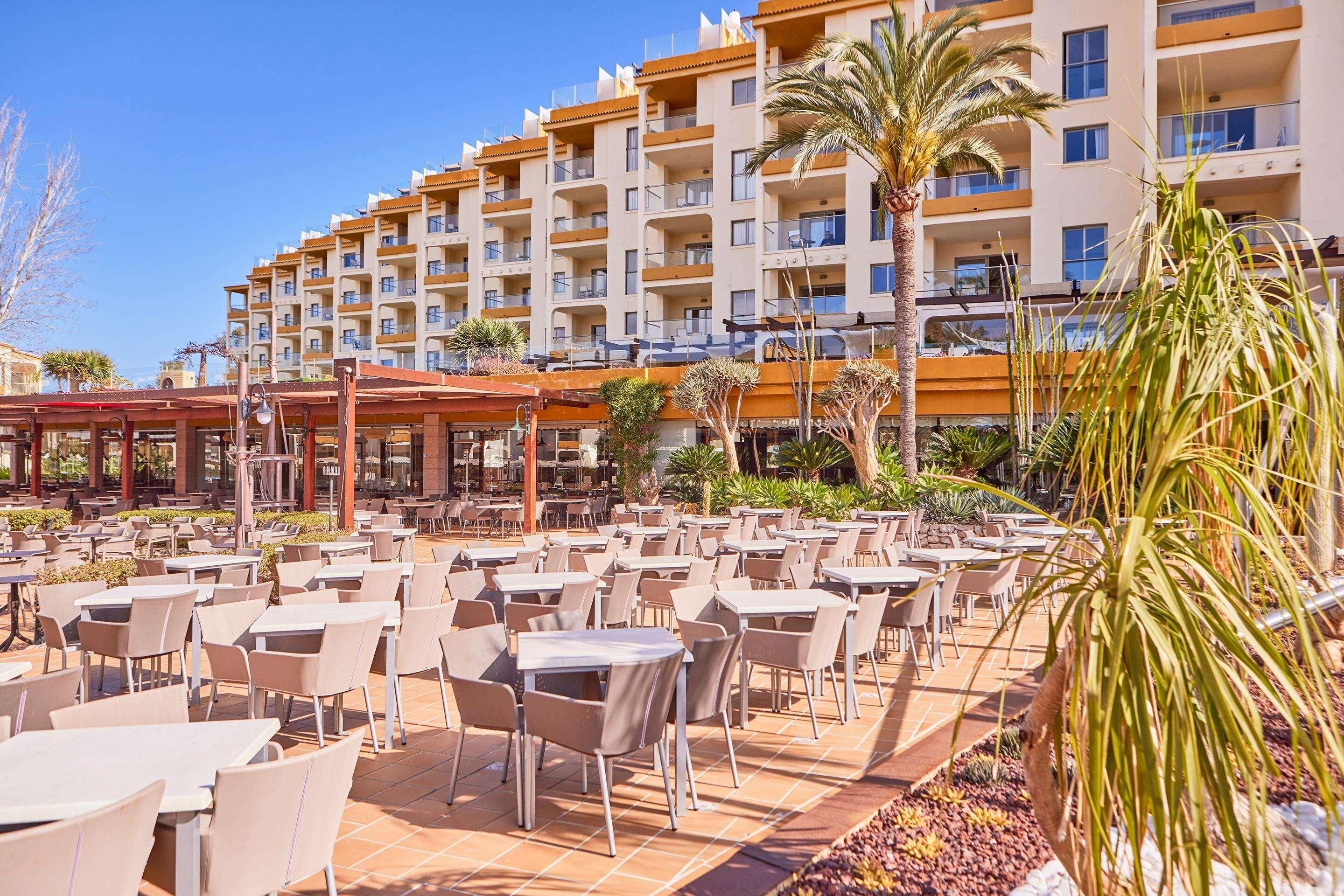 A hotel with outdoor dining area, multiple floors, and balconies.