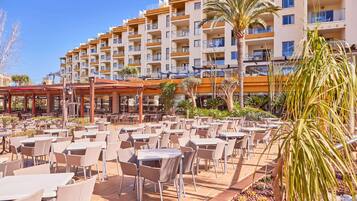 A hotel with outdoor dining area, multiple floors, and balconies.