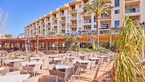 Un hotel con zona de comedor al aire libre, varios pisos y balcones.
