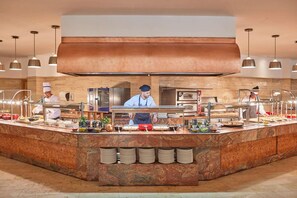 A buffet setup with multiple serving stations, a large central counter, and a chef at work. - Zafiro Tropic (Alcúdia)