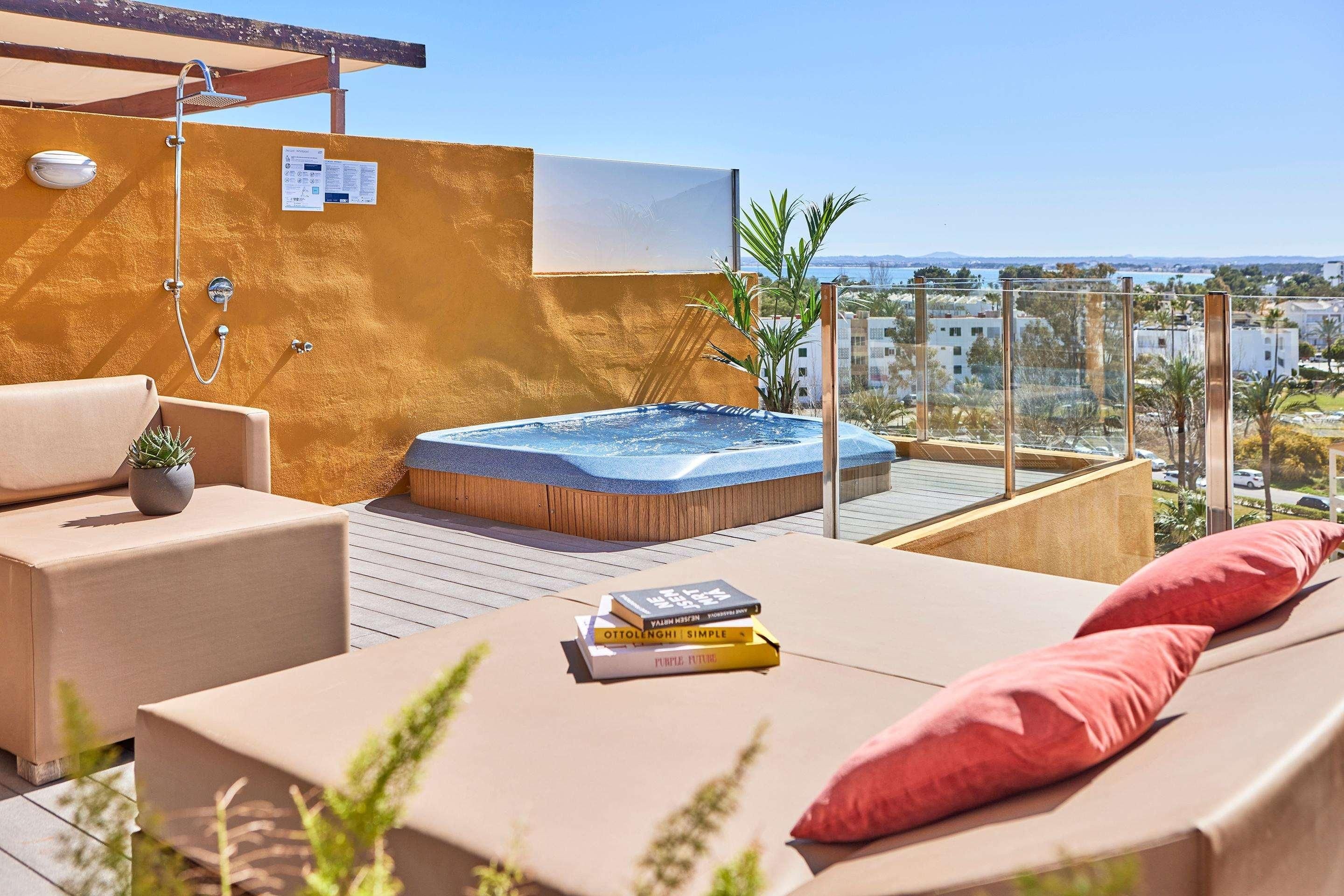 A rooftop terrace with a hot tub, lounge chairs, and a view of the city.