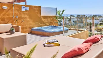 Una terraza en la azotea con jacuzzi, sillones de descanso y vistas a la ciudad.