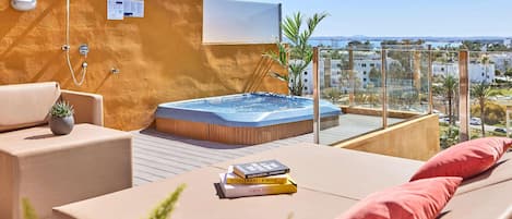 Eine Dachterrasse mit Whirlpool, Liegestühlen und Blick auf die Stadt.