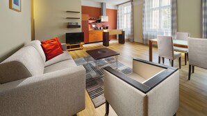 A modern living room with a sofa, coffee table, and a dining area with chairs. - Mamaison Residence Belgicka (Prague)