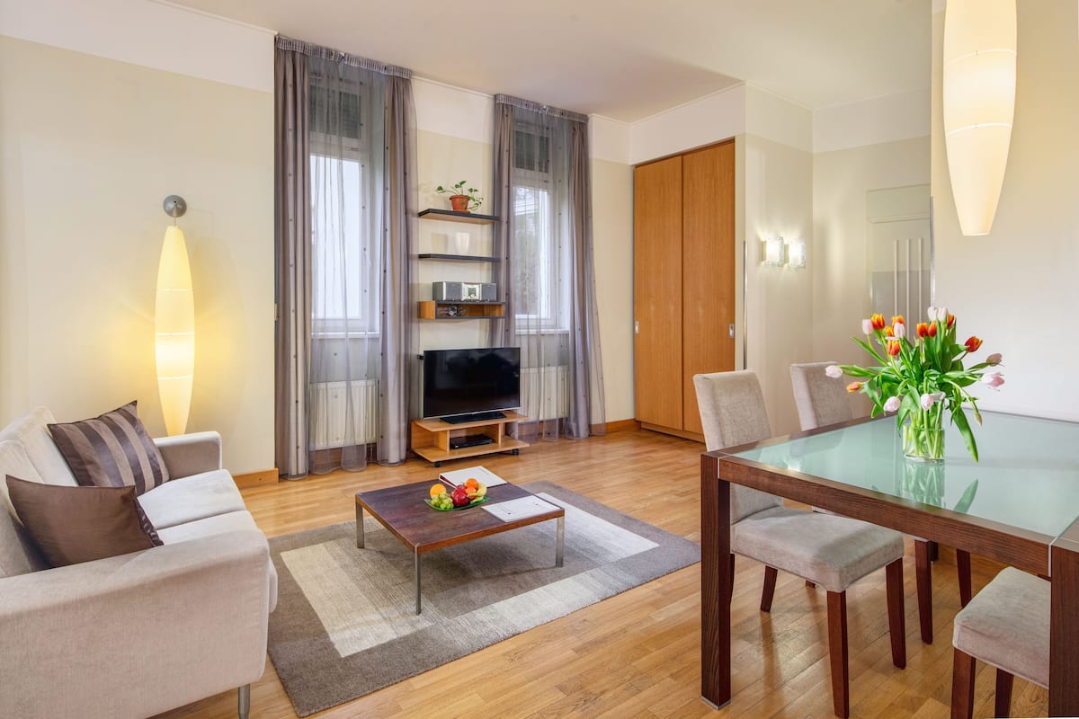 Una sala de estar moderna con sofá, televisor, mesa de centro y mesa de comedor con sillas.
