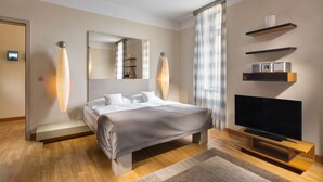 A modern hotel room with a large bed, a flat-screen TV, built-in shelves, and a large mirror. - Mamaison Residence Belgicka (Prague)