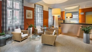 A hotel lobby with wicker furniture, a reception desk, and potted plants. - Mamaison Residence Belgicka (Prague)