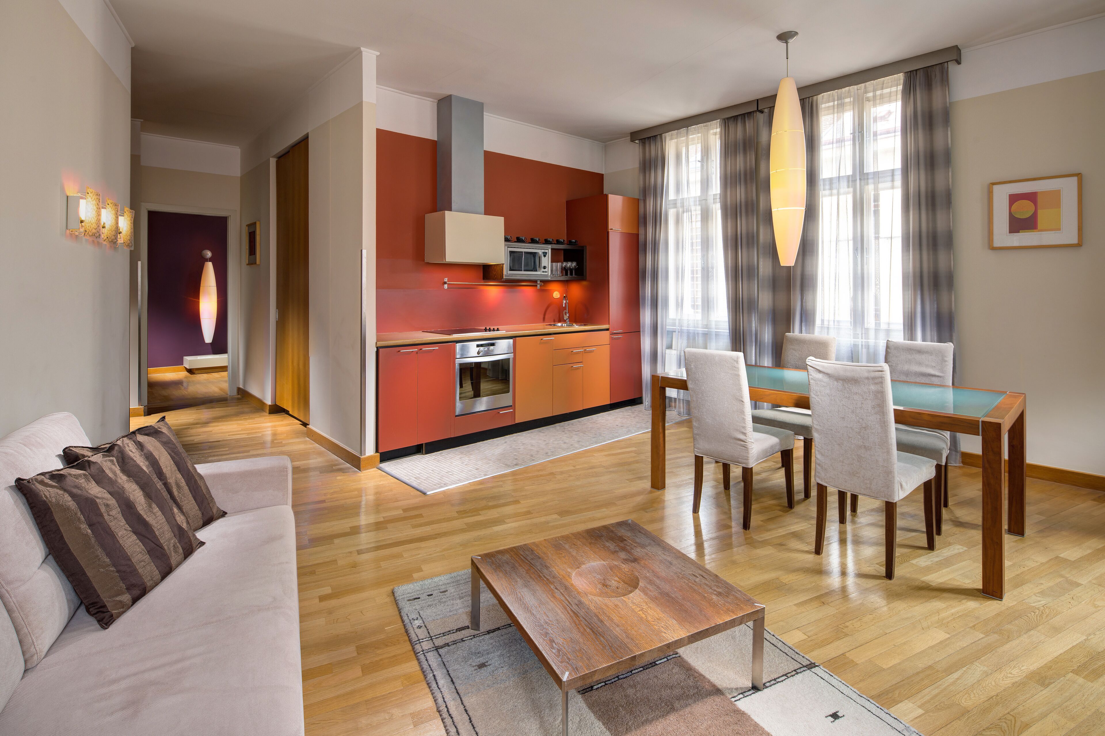 A modern living room with a sofa, coffee table, and dining area with chairs and a table.