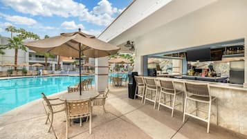 A poolside bar area with a pool, lounge chairs, and umbrellas.