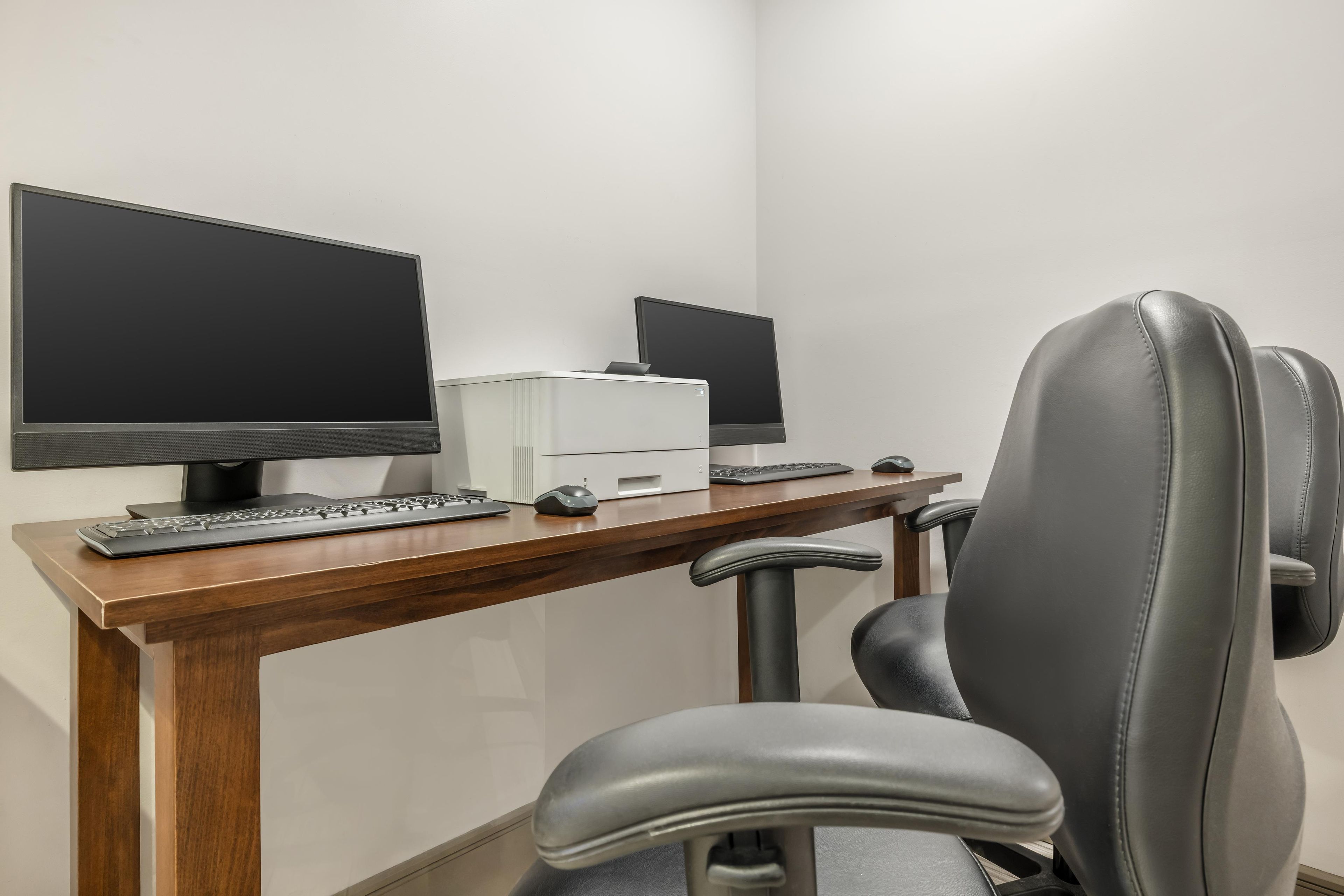A workspace with two monitors, a keyboard, a mouse, and a chair.