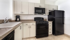 A compact kitchen with a sink, stove, microwave, and refrigerator.