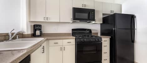 Cocina compacta con lavabo, estufa, microondas y refrigerador.