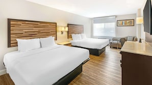 Ein Hotelzimmer mit zwei Betten, einem Schreibtisch, einem Stuhl und einem Fernseher.