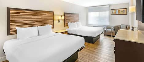 Een hotelkamer met twee bedden, een bureau, een stoel en een televisie.