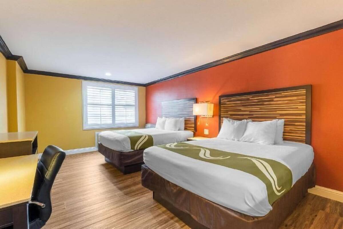 Une chambre d’hôtel avec deux lits, un bureau et une chaise.