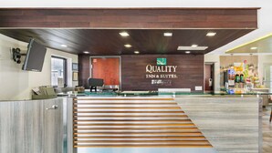 Ein Empfangsbereich mit einem Schild, das "Quality Inn & Suites" zeigt, und einer Treppe zu den oberen Etagen.
