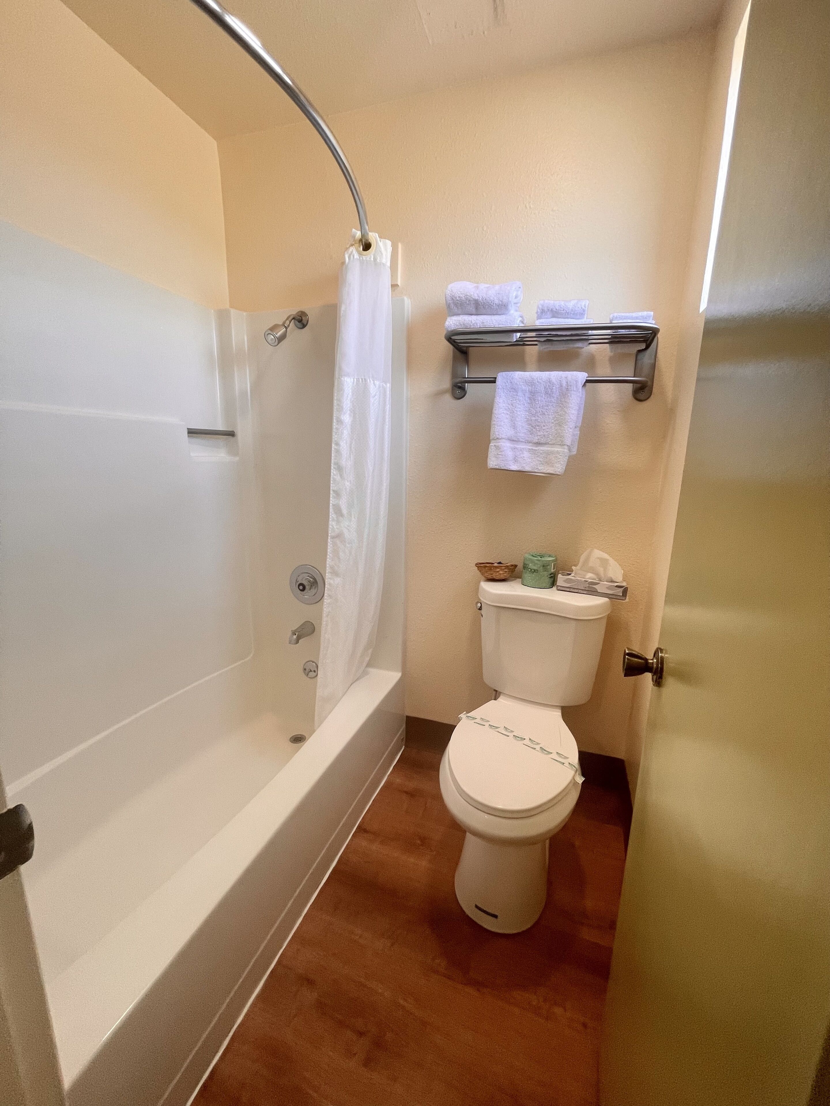 A bathroom with a bathtub, toilet, and a towel rack.