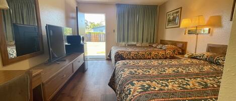 Habitación de hotel con dos camas, televisión, escritorio y ventana con cortinas.