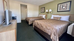 A hotel room with two beds, a desk, a television, and two lamps. - Regency Inn (Lakeport)