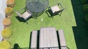 Un espacio al aire libre con una mesa redonda y dos sillas, rodeado por un banco de madera.